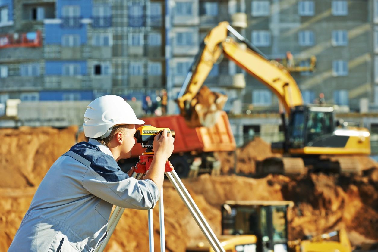 Surveyor working with theodolite transit equipment at construction site